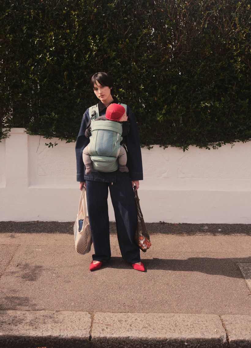 A parent carrying a baby in a NUBE carrier on a London street