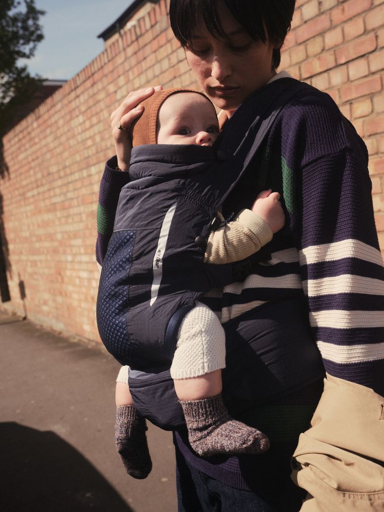 A parent holding a baby close in a NUBE carrier